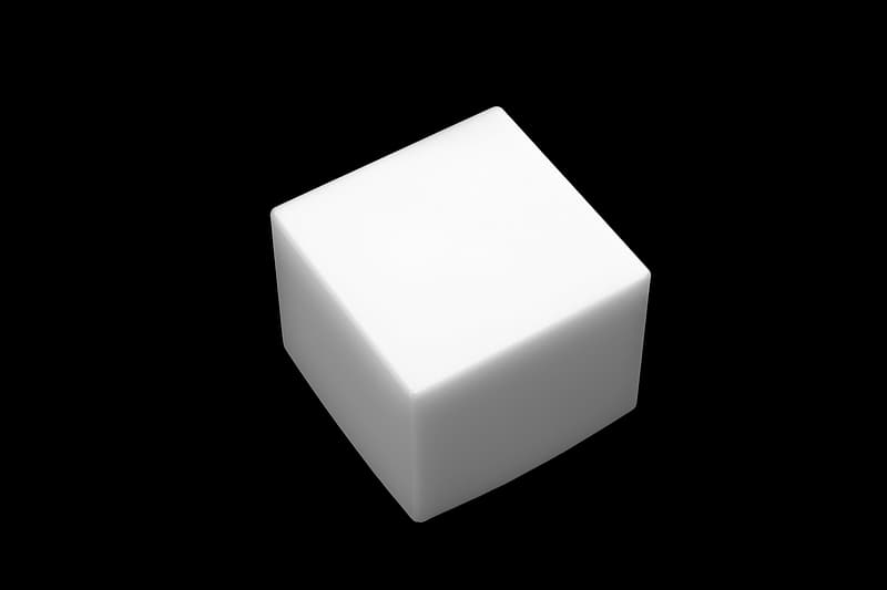 An isometric photo of a white cube. It has a pitch black background and shadows going down its sides.